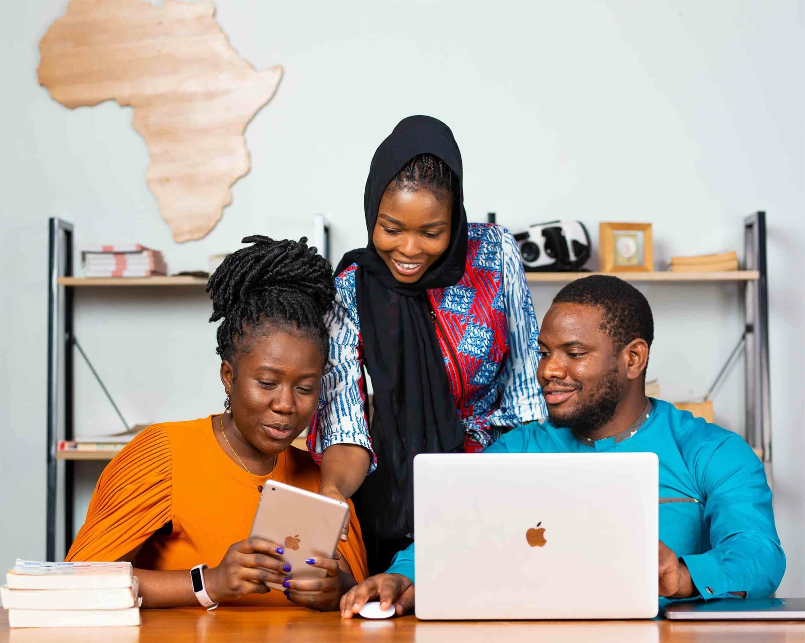 Three people looking at a laptop and tablet together