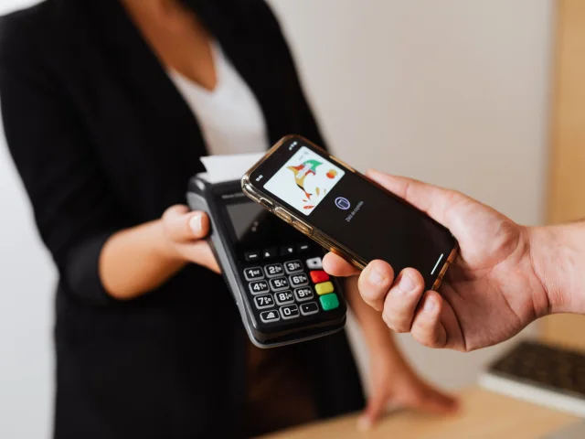 A customer making a contactless phone payment on a point-of-sale terminal