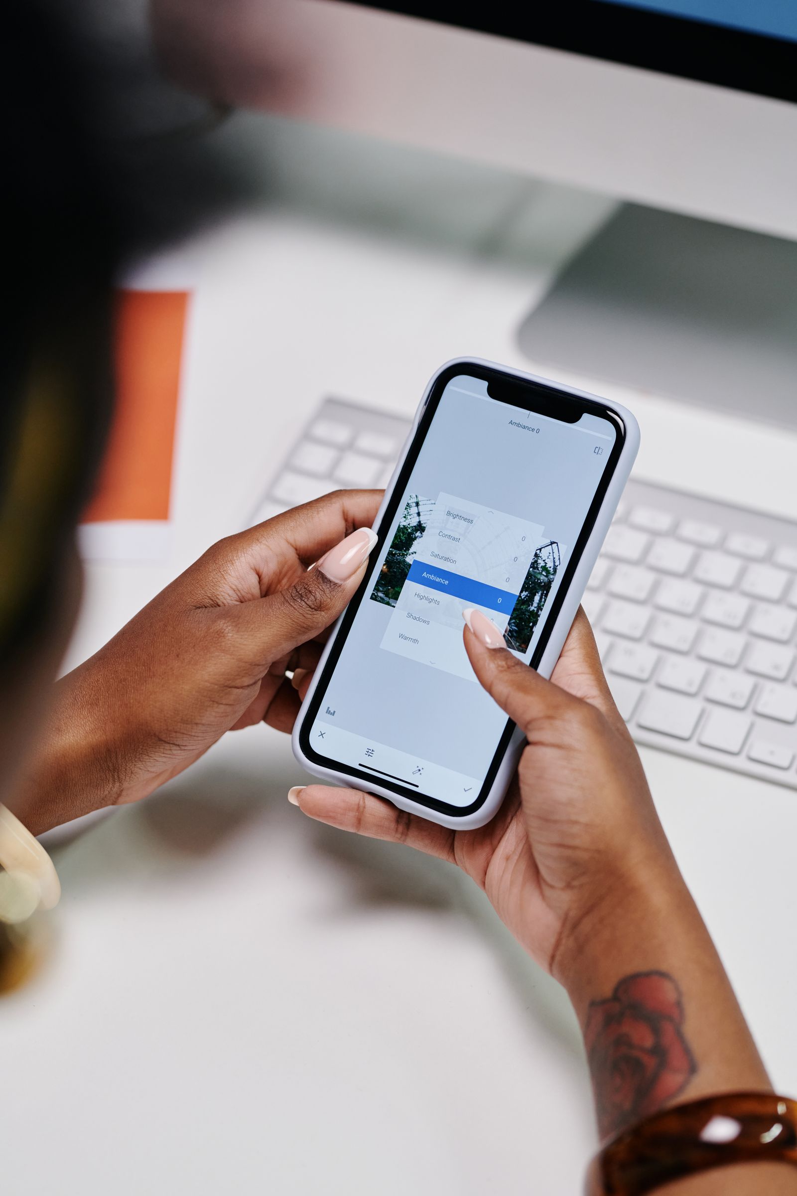 Person using an iPhone editing app at a desk